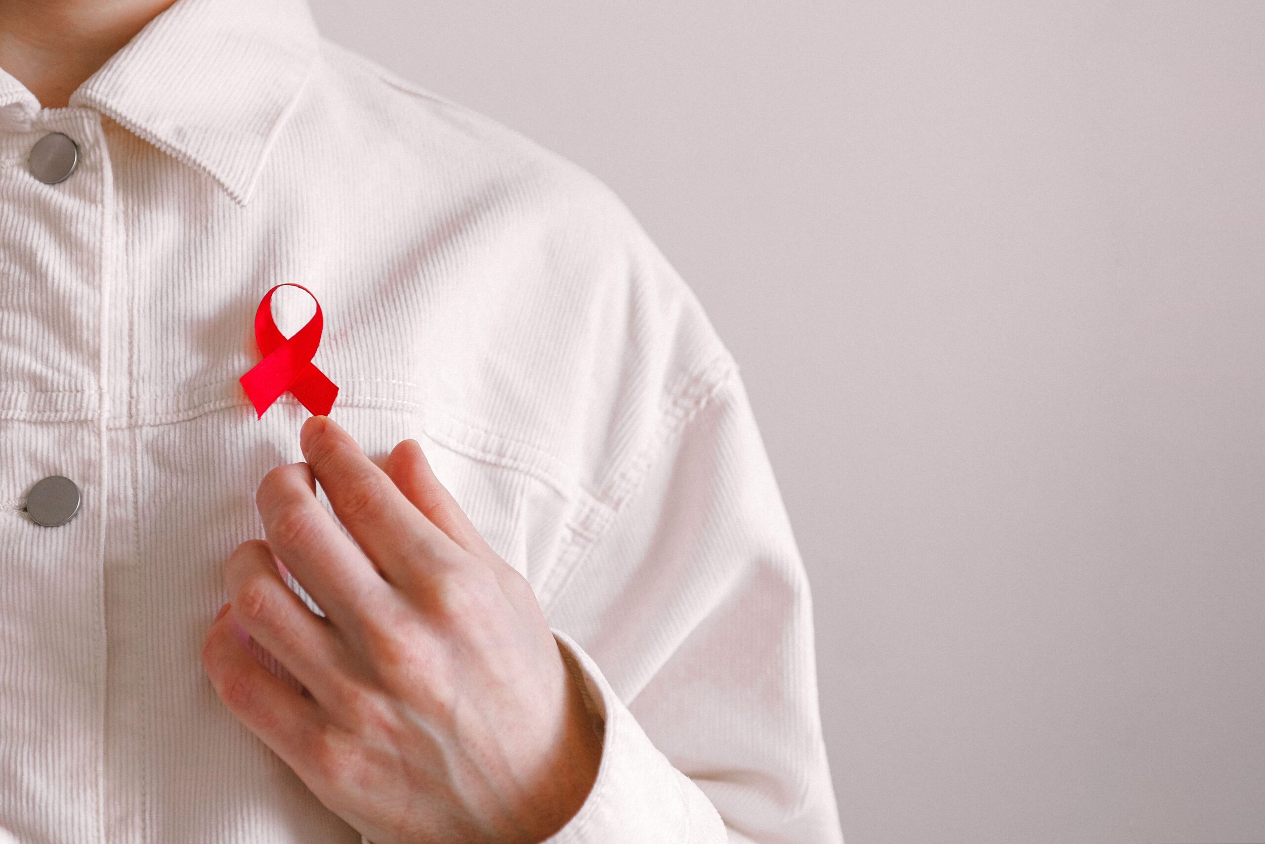 Close-up of a red ribbon on a white shirt symbolizing AIDS awareness and support.